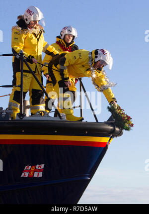 Mitglieder der Anstruther Royal National Lifeboat Institution (RNLI) Weihnachten ein Kranz an der Vorderseite Ihrer Boot befestigen, wie Sie zusammen vor die festliche Zeit für praktische Übungen und Übungen an das Rettungsboot Station in Anstruther, Fife. Stockfoto