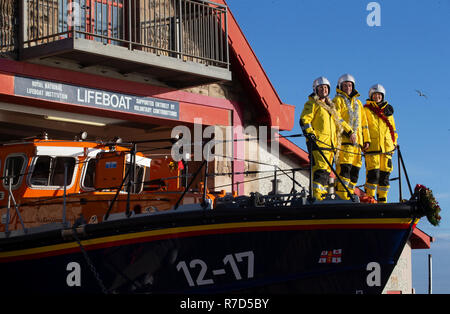 Mitglieder der Anstruther Royal National Lifeboat Institution (RNLI) Weihnachten ein Kranz an der Vorderseite Ihrer Boot befestigen, wie Sie zusammen vor die festliche Zeit für praktische Übungen und Übungen an das Rettungsboot Station in Anstruther, Fife. Stockfoto