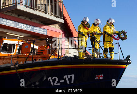 Mitglieder der Anstruther Royal National Lifeboat Institution (RNLI) Weihnachten ein Kranz an der Vorderseite Ihrer Boot befestigen, wie Sie zusammen vor die festliche Zeit für praktische Übungen und Übungen an das Rettungsboot Station in Anstruther, Fife. Stockfoto