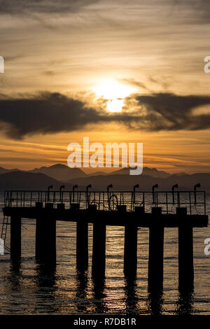 Die Silhouetten der Flughafen Lichtmasten früh am Morgen bei Sonnenaufgang auf der Insel Kerkira, Korfu, Griechenland. Landschaft golden Kurven der Bergkette Stockfoto