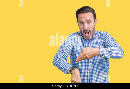 Stattliche mittleren Alter elegante älterer Mann über isolierte Hintergrund in Eile hin zu beobachten, Ungeduld, verärgert und wütend für Termin Verzögerung Stockfoto