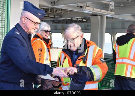 Kapitän Michael Balding, Stellvertretender Sektor Kommandant, Coast Guard Sektor Puget Sound, gibt James Patheal, 2 Gehilfen, Washington State Ferries, eine Münze ihm nach Vorlage einer Bescheinigung des Verdienstes in einer Zeremonie an der Seite des Motor Schiff Kaleetan auf dem Weg nach Seattle von Bremerton, Dez. 3, 2018. Der Ehrenbrief wurde in Anerkennung der Rettungsmaßnahmen Patheal als Reaktion auf eine Person im Wasser am 12.08.16., 2018. Us-Küstenwache Stockfoto