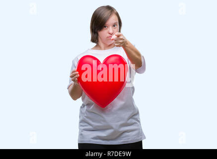 Junge erwachsene Frau mit Down Syndrom halten roten Herzen über isolierte Hintergrund zeigt mit dem Finger auf die Kamera und an Sie, Hand, Zeichen, positiv und Stockfoto
