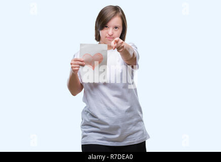 Junge erwachsene Frau mit Down Syndrom halten roten Herzen Karte über isolierte Hintergrund zeigt mit dem Finger auf die Kamera und an Sie, Hand, Zeichen, positiv Stockfoto