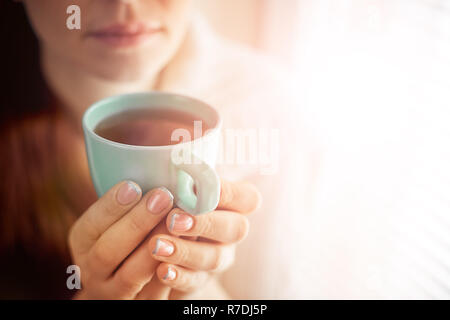 Tee trinken, sitzen auf dem Fenster der Kaukasischen schöne Frau mittleren Alters mit roten Haaren, Toning Stockfoto