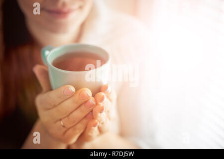 Tee trinken, sitzen auf dem Fenster der Kaukasischen schöne Frau mittleren Alters mit roten Haaren, Toning Stockfoto