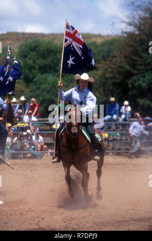 Weibliche Mitfahrer an australischen RODEO AM AUSTRALIA DAY HALTEN DIE AUSTRALISCHE FLAGGE LÄUTET DEN BEGINN DES RODEO, NEW SOUTH WALES Stockfoto