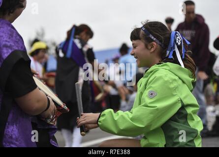 Ein junges Mädchen schließt sich mit der Bühne Darsteller auf der Kadena Special Olympics, Nov. 4, 2017, bei Kadena Air Base, Japan. Tausende von Zuschauern aus Japan und den USA kamen etwa 900 Athleten und Künstler die Teilnahme an der 18. jährlichen KSO Spiele und Kunst zeigen zu unterstützen. Stockfoto