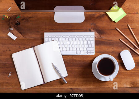 Arbeitsplatz Hintergrund, oben über der Schreibtisch mit Computer Monitor Tastatur öffnen Sie Notizbuch mit Stift und Kaffee auf braune Holztisch, Büro su Stockfoto