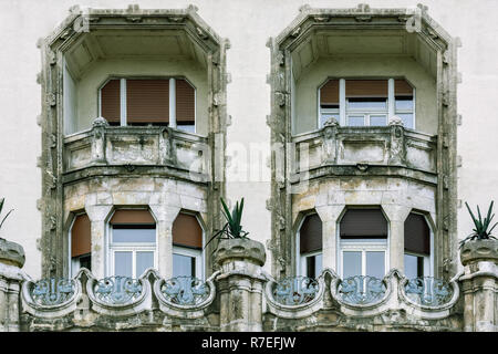 Zwei Fenster in ein altes Haus mit einem Zwischengeschoss und eine Loggia und einen Zaun mit einem geschmiedeten Gitter dargestellt. Stockfoto