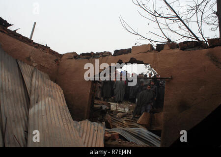 Srinagar, Indien. 9. Dez 2018. Kaschmirische Muslime beobachten beschädigten Hauses. Nach einer nächtlichen Begegnung, die am Rande des Dorfes an Mujgund brach, rund 11 km von Srinagar. am Samstag Abend. 3 Militante erschossen, Soldat verletzt In der Begegnung. Während der Operation, Sicherheitskräfte, flammte die Hälfte Wohnhäuser Dutzend beim Versuch, die Militanten, die sie zogen von Haus zu Haus die Sicherheitskräfte zu entziehen, zu neutralisieren. Wie ein Polizeisprecher mitteilte. © sofi Suhail/Alamy leben Nachrichten Stockfoto