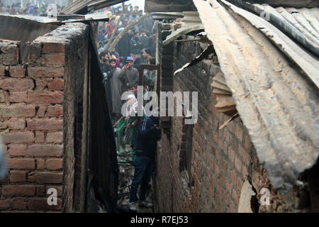 Srinagar, Indien. 9. Dez 2018. Kaschmirische Muslime beobachten beschädigten Hauses. Nach einer nächtlichen Begegnung, die am Rande des Dorfes an Mujgund brach, rund 11 km von Srinagar. am Samstag Abend. 3 Militante erschossen, Soldat verletzt In der Begegnung. Während der Operation, Sicherheitskräfte, flammte die Hälfte Wohnhäuser Dutzend beim Versuch, die Militanten, die sie zogen von Haus zu Haus die Sicherheitskräfte zu entziehen, zu neutralisieren. Wie ein Polizeisprecher mitteilte. © sofi Suhail/Alamy leben Nachrichten Stockfoto