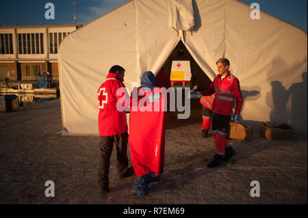 Malaga, Spanien. 9 Dez, 2018. Ein Mitglied des spanischen Roten Kreuzes gesehen helfen ein Wanderarbeitnehmer aus einem Zelt des spanischen Roten Kreuzes nach Ihrer Ankunft im Hafen von Málaga in Spanien Maritime Rescue Service Über 239 Migranten an Bord Jollen auf der Alboran See gerettet und brachte sie nach Malaga Hafen, von wo aus sie durch das Spanische Rote Kreuz unterstützt wurden. Insgesamt wurden 27 Migranten gerettet am Samstag am Alboran Meer und die Straße von Gibraltar. Credit: Jesus Merida/SOPA Images/ZUMA Draht/Alamy leben Nachrichten Stockfoto