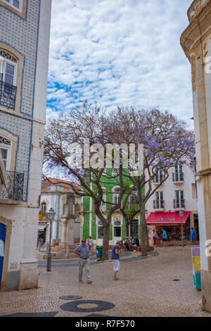 Lagos, Portugal - 27. Juni 2018: Touristen halten an Geschäften entlang der gefliesten Straßen von Lagos an einem sonnigen Tag. Stockfoto