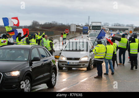 Roppenheim, Frankreich. 08 Dez, 2018. Autos fahren durch den Protest. Die Demonstranten jubeln, wenn die Treiber ihre Unterstützung zeigen. Rund 100 Französische gelbe Weste Aktivisten protestierten auf einer Straße in der Nähe der Französisch Deutsch Grenzübergang bei Roppenheim gegen die französische Regierung. Sie wurden von einigen Aktivistinnen aus der Deutschen rechten Gruppen unterstützt. Sie waren Teil der grösseren gelbe Weste Protestbewegung in Frankreich, die in den vergangenen 4 Wochen in ganz Frankreich protestiert. Quelle: Michael Debets/Pacific Press/Alamy leben Nachrichten Stockfoto