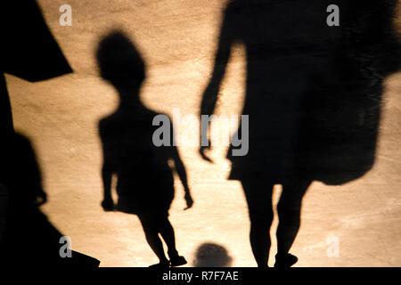 Verschwommene Schatten von Kind und Mutter zu Fuß auf der Promenade im Sommer Sonnenuntergang Stockfoto