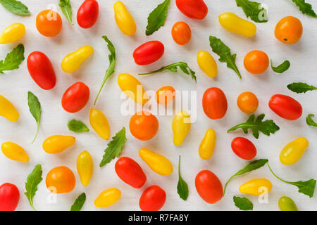 Muster der frischen bunten Gelbe und Rote homegrown Bio Tomaten und grüne Blätter treibt der Zichorie, auf weißem Hintergrund verbreiten. Von oben gesehen in Ful Stockfoto