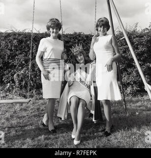 1965, historische, drei attraktiven jungen Damen zusammen für ein Foto posieren durch einen Outdoor Swing, der Sieger in der Krone und die zwei Läufer im Fräulein Prestwood beauty contest auf der lokalen Dorffest, Bucks, England, Großbritannien Stockfoto