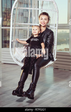 Junge Mutter und Tochter in Leder schwarz passt zu lächeln. Stockfoto