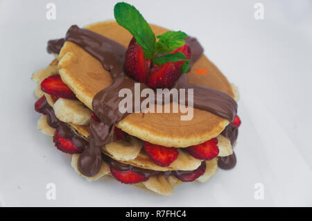 Pfannkuchen mit frischen Erdbeeren und Bananen aufgestockt auf schokoladensauce mit isolierten weißen Hintergrund Stockfoto