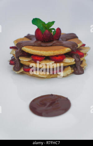 Pfannkuchen mit frischen Erdbeeren und Bananen aufgestockt auf schokoladensauce mit isolierten weißen Hintergrund Stockfoto