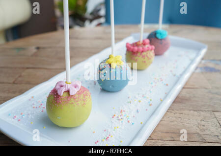 Bunte Kugel lolipop candy Sticks auf weiße Platte auf Holz Tisch Stockfoto