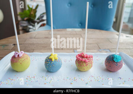 Bunte Kugel lolipop candy Sticks auf weiße Platte auf Holz Tisch Stockfoto