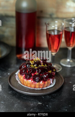 Süße Mahlzeit für zwei: Rotwein, Kuchen mit Puderzucker und Obst, French Pastetchen Stockfoto