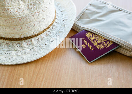 Reiseanliegen Konzept für Auslandsreisen Britischer biometrischer Reisepass in einer Brieftasche mit Damensonnenhut auf einer Tischplatte. England, Großbritannien Stockfoto