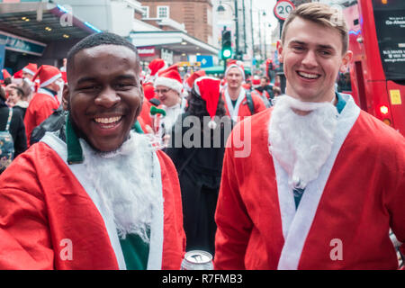 London, UK - Dezember 2018: Zwei Freunde in santa Outfits für Foto posiert während ein Themenbuffet gekleidet SantaCon Ereignis Stockfoto