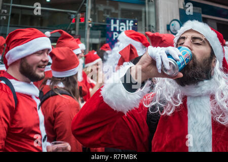 London, UK, Dezember 2018: der Mann, der in santa Outfit trinken alkoholische Bier aus der Dose während ein Themenbuffet gekleidet SantaCon Ereignis Stockfoto