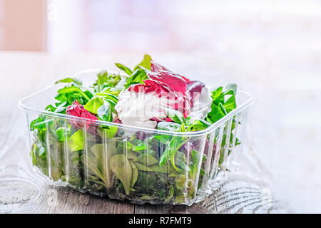 Mix aus frischen organischen Salate in durchsichtigen Verpackungen auf einen hölzernen Tisch. Kopieren Sie Platz. Stockfoto