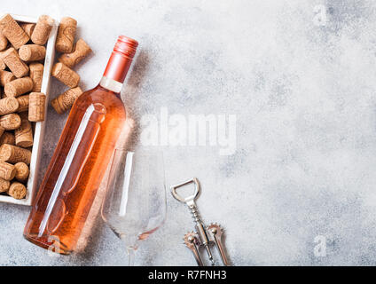 Flasche und Gläser pink rose Wein mit Box von Korken und Korkenzieher Dosenöffner auf Stein Küchentisch Hintergrund. Ansicht von oben. Stockfoto