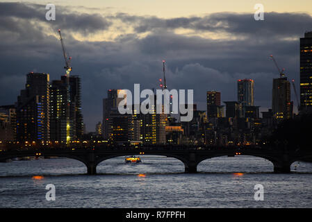 Skyline von London in der Abenddämmerung mit Licht auf die Gebäude in Abend. River Thames River traffic. Baukräne. Lambeth Brücke. Nine Elms. Gebäude Stockfoto