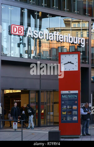 Aschaffenburg, Deutschland - November 17, 2018: Reisende stehen vor der modernen Glasfassade und einer Standuhr der Aschaffenburg zentrale s Stockfoto