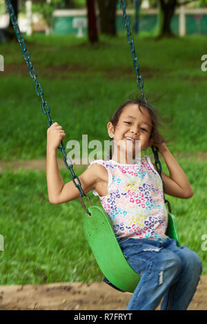 Asiatische Mädchen schwingen und lächelnd. Filipina Kid. 7 Jahre alt. Stockfoto