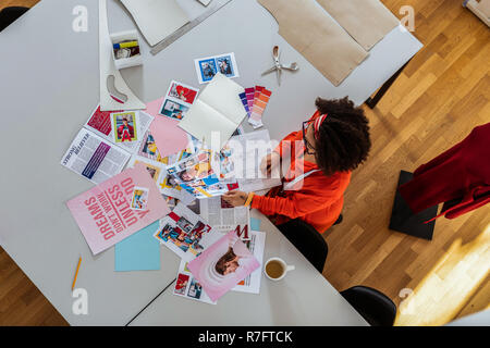 Ungewöhnlich helle curly Frau erhalten Inspiration von Zeitschriften Zeitungsausschnitte Stockfoto