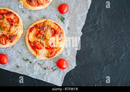 Mini Pizza margheritas auf einem Pergament Papier auf einem schwarzen Stein ba Stockfoto