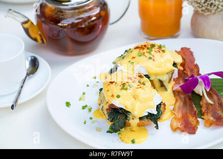 Schließen Sie herauf frische Eier Benedikt Frühstück mit schwarzem Kaffee und Orangensaft Stockfoto