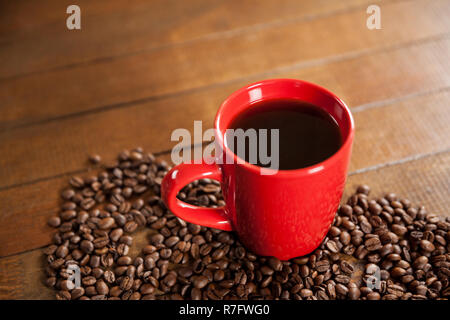Tasse Kaffee und Kaffeebohnen auf Holztisch Stockfoto