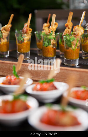 Köstliche Fleisch Snacks mit Soße auf kleinen Tellern und in Shot Gläser am Buffet serviert. Catering Konzept Stockfoto