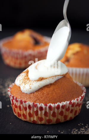 Muffins mit Sahne und Löffel Stockfoto