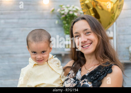 Mama hält ein Kind auf dem Arm. Eine glückliche Familie. Junge Mutter ihr Baby in die Arme und streichelte Kind meiner Mutter litso. Portret Mutter und wenig Stockfoto