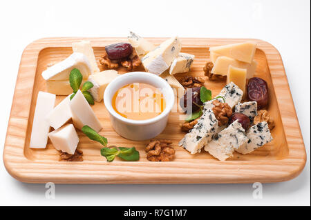 Käseplatte mit Honig, Nüsse und Termine. Holz Platine mit weißem Hintergrund Stockfoto