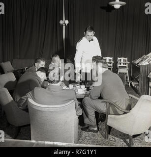 1950er Jahre, Piloten in Taste Stühle um einen Tisch in einem Gespräch sitzen, Kaffee in einem Flughafen Lounge serviert von einer weiß beschichteten männliche Kellner, Dublin Airport, Dublin, Irland Stockfoto