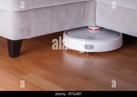 Roboter Staubsauger läuft auf Parkettboden. Moderne Reinigungstechnik und Sauberkeit. Stockfoto