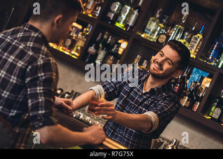 Junge Barkeeper stehen an der Theke geben Kunde cocktail heiter Stockfoto