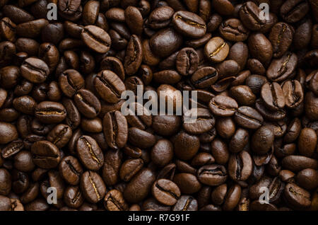 Leuchtet dunkel geröstete Kaffeebohnen, die zusammen gestapelt und Befüllen von Frame a Hintergrund Textur in mehreren Farben Braun und Gold zu erstellen. Stockfoto