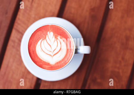 Eine Tasse Kaffee mit Latte Art auf Holztisch getönten in trendigen lebende Koralle Farbe. Farben des Jahres 2019. Stockfoto