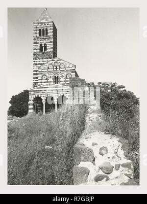 Sardinien Sassari Sassari Umgebung SS. Trinità di Saccargia Camaldolite, das ist mein Italien, die italienische Land der visuellen Geschichte, Außenansichten einer romanischen Kirche aus dem 12. Jahrhundert gehören eine gestreifte dunklem Basalt und weißen Kalkstein Fassade ein Turm von Pisa und Lucchesian Einfluss und dekoriert/groteske Hauptstädte. Antiquitäten zwei Säulen und Kapitelle des Portikus. Foto 1983 Stockfoto